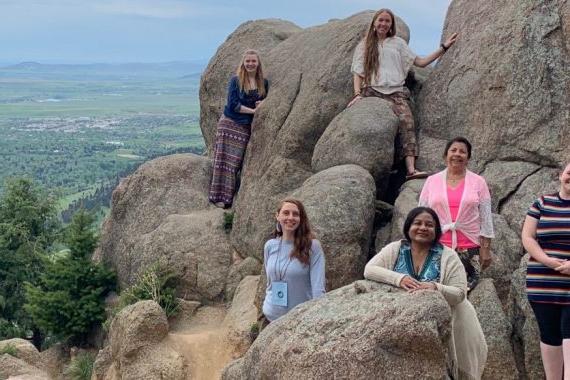 Students standing around a large rock formation overlooking a valley